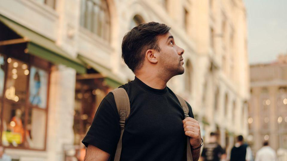 Tourist blickt in einer Altstadt auf historische Fassaden